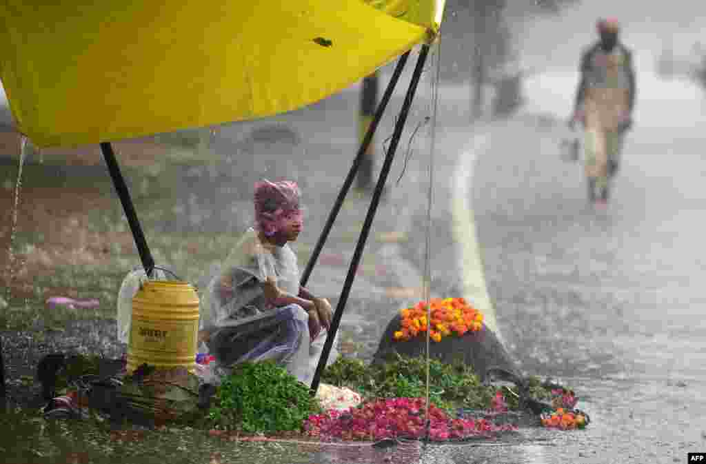 A boy waits for customers at a flower stall during heavy rain in Allahabad, India.