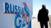 A journalist speaks on a cell phone next to a sign for the G20 summit in St. Petersburg, Russia on Sept. 4, 2013. 