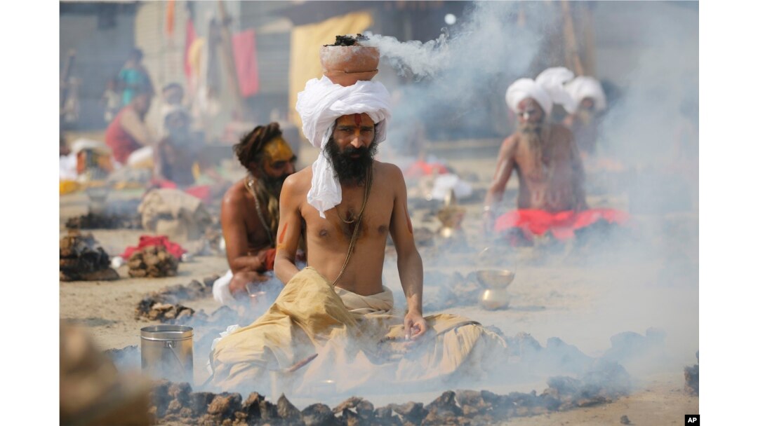 Hindu holy men burn dried cow dung cakes as they perform a ritual at Sangam, confluence of rivers Ganges and Yamuna on "Basant Panchami" day at the annual traditional fair of Magh Mela in Allahabad, India, Monday, Jan. 22, 2018.