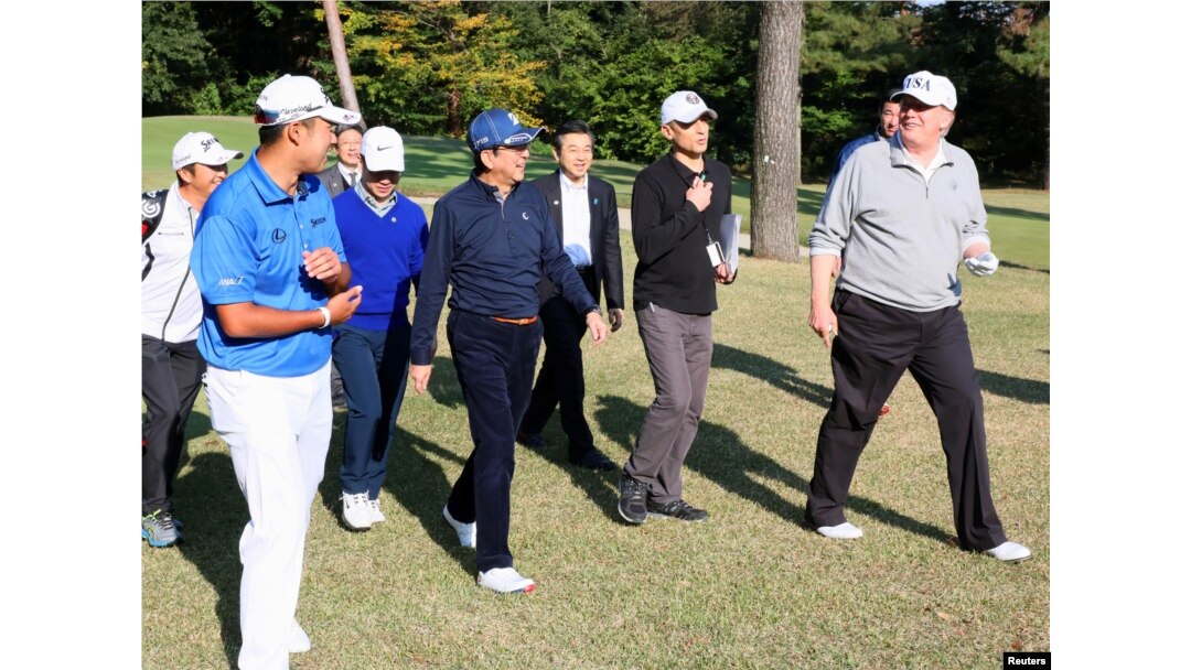 U.S. President Donald Trump (R) talks with Japan's PM Shinzo Abe as Japanese professional golfer Hideki Matsuyama looks on, as they play golf at the Kasumigaseki Country Club in Kawagoe, in this photo released by Japan's Cabinet Public Relations Office vi