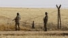 FILE - Turkish soldiers stand guard as a Syrian refugee boy waits behind border fences to cross into Turkey on the Turkish-Syrian border, near the southeastern town of Akcakale in Sanliurfa province, Turkey, June 5, 2015. A London-based Syrian monitoring group has accused Turkish border guards of having killed dozens of Syrian refugees in 2016 alone.