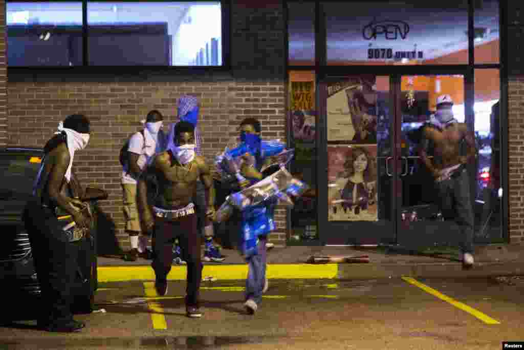 Niqoblangan shaxslar do'konlardan birini tunamoqda, Ferguson, 16-avgust, 2014-yil.