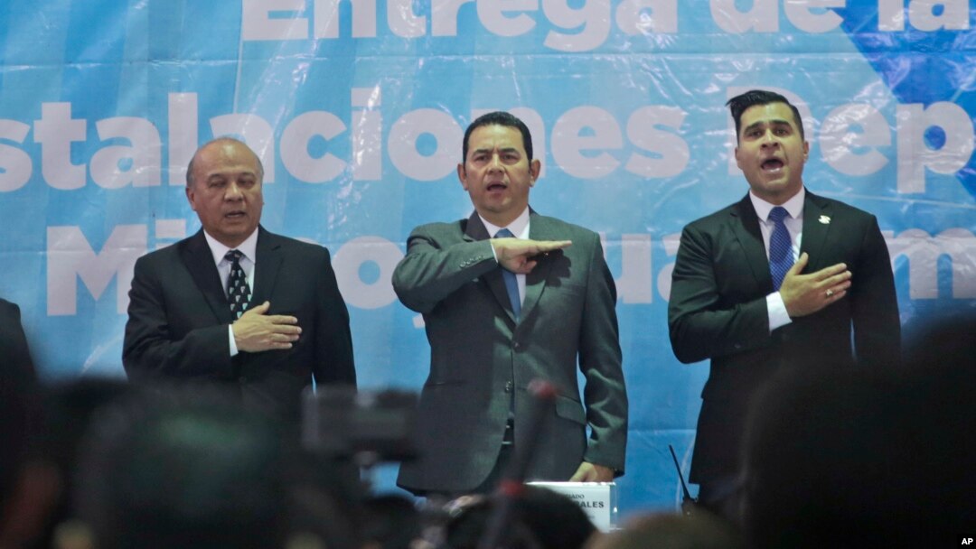 Guatemalan President Jimmy Morales, center, sings the national anthem, during the inauguration of a soccer field in Mixco, Guatemala, Sept. 17, 2018. 