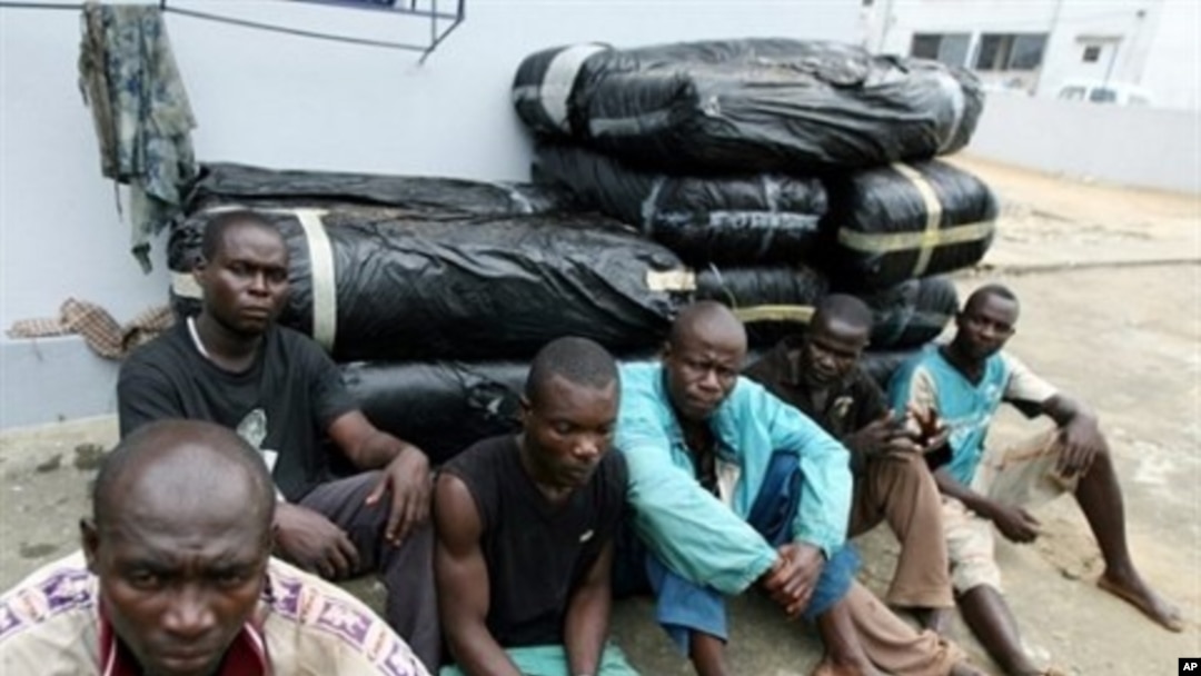 Ghanaian drug-runners sitting in front of bales of cannabis seized by the anti-drug section of the Ivorian gendarmerie in Abidjan (File Photo)