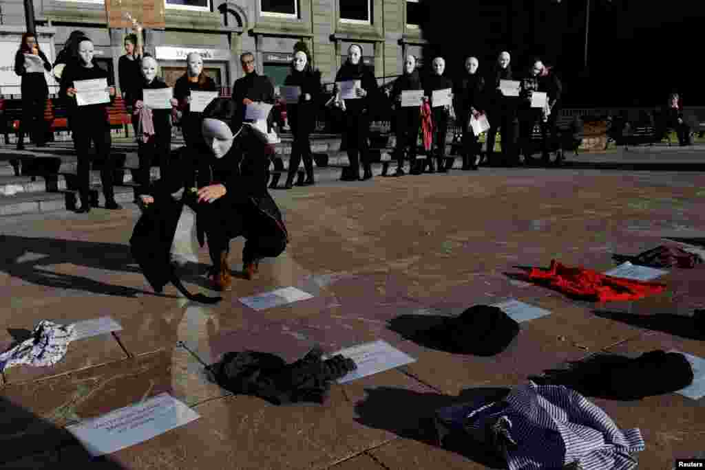 Gender studies students wear masks and hold signs bearing names and ages during a performance to commemorate victims of gender violence, during the U.N. International Day for the Elimination of Violence against Women in Oviedo, Spain, Nov. 25, 2016.