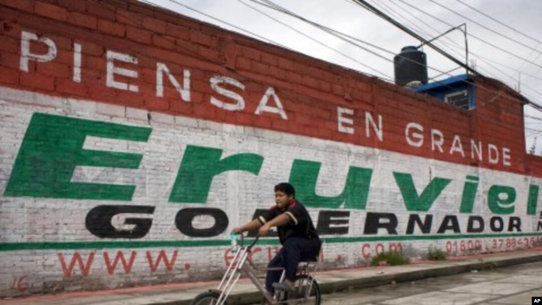 A cyclist rides past a mural for Eruviel Avila, candidate for governor of the state of Mexico for the Institutional Revolutionary Party (PRI) in Toluca, July 2, 2011