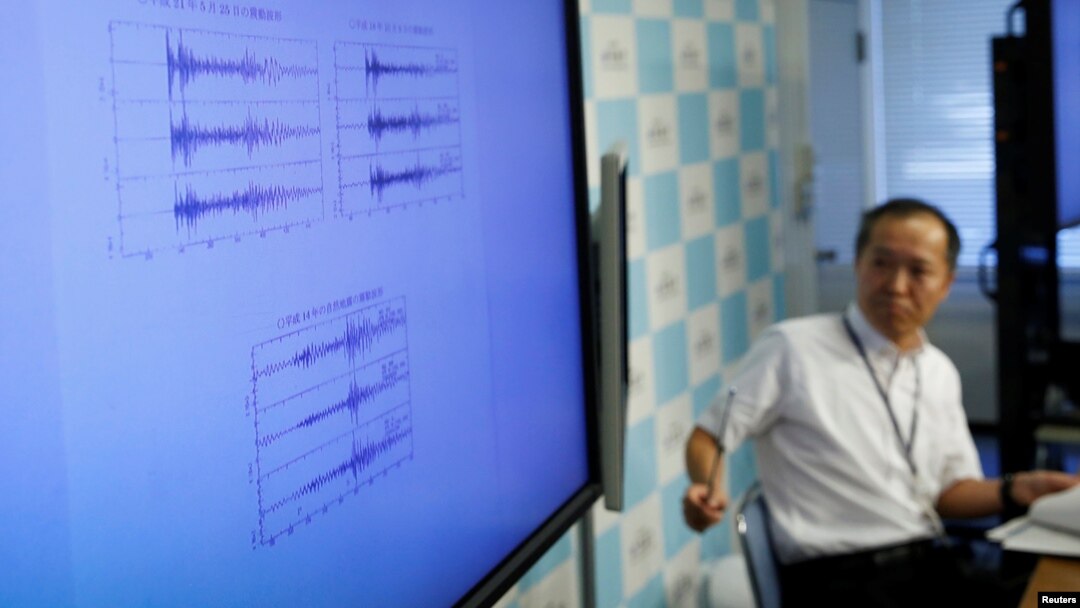FILE - Japan Meteorological Agency's earthquake and tsunami observations division director Toshiyuki Matsumori speaks next to a monitor showing graphs of ground motion during a news conference at the agency, in Tokyo, Japan, Sept. 3, 2017.