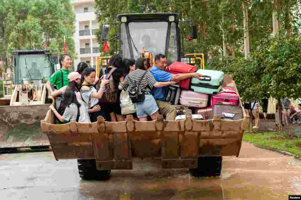 Students are transferred by a forklift through a flooded area at a college in Guilin, Guangxi province, China, July 3, 2017.