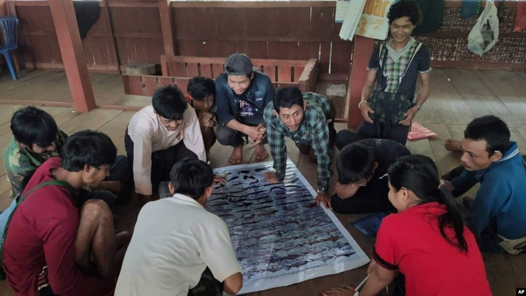 In this March 2020 photo provided by the Southern Youth Development Organization, community members check information in a poster they produced which documents local fish, before publication, in the Lenya area of the Tanintharyi region in southern Myanmar.