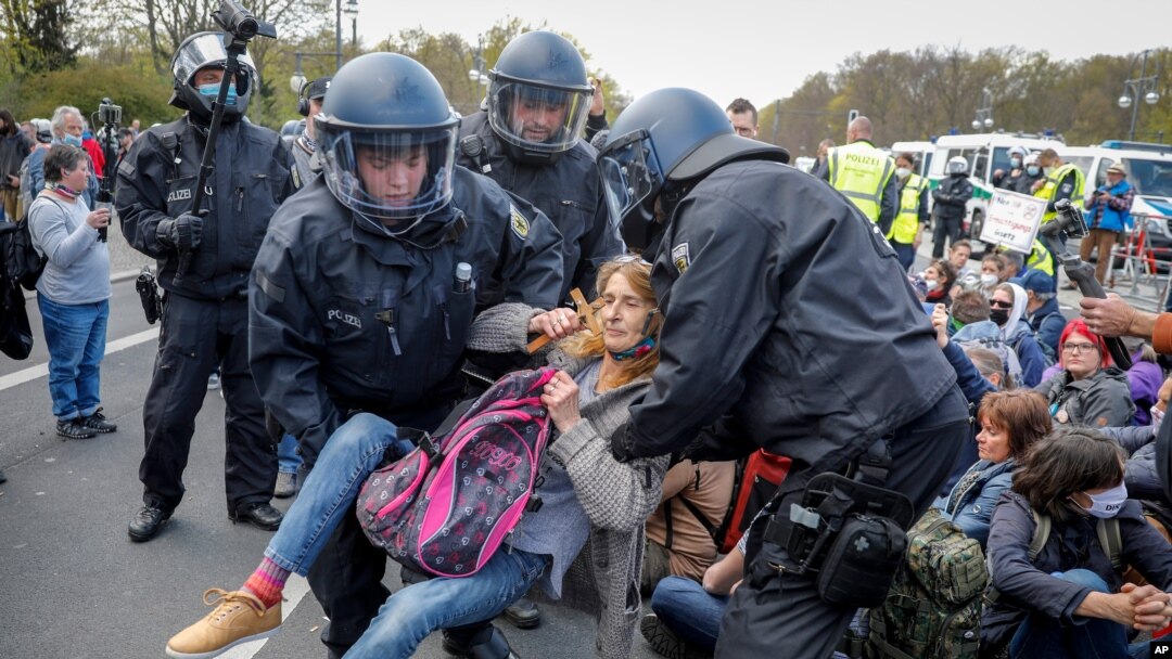 Police officers carry away a demonstrator after police stop a protest against the German government's coronavirus restrictions, in Berlin, Germany, April 21, 2021.