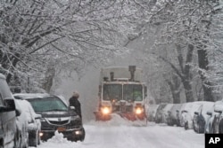 A snow plow waits for a vehicle to move out of its parking spot in Brooklyn's Flatbush neighborhood, Feb. 3, 2014, in New York.