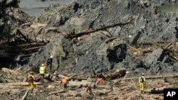 Workers search an area next to large mounds of dirt near Darrington, Washington state, in the debris field of the deadly mudslide, April 1, 2014.