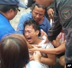 Police and rescuers comfort a crying passenger after he was brought ashore from a capsized passenger ferry July 2, 2015, in Ormoc city, central Philippines.