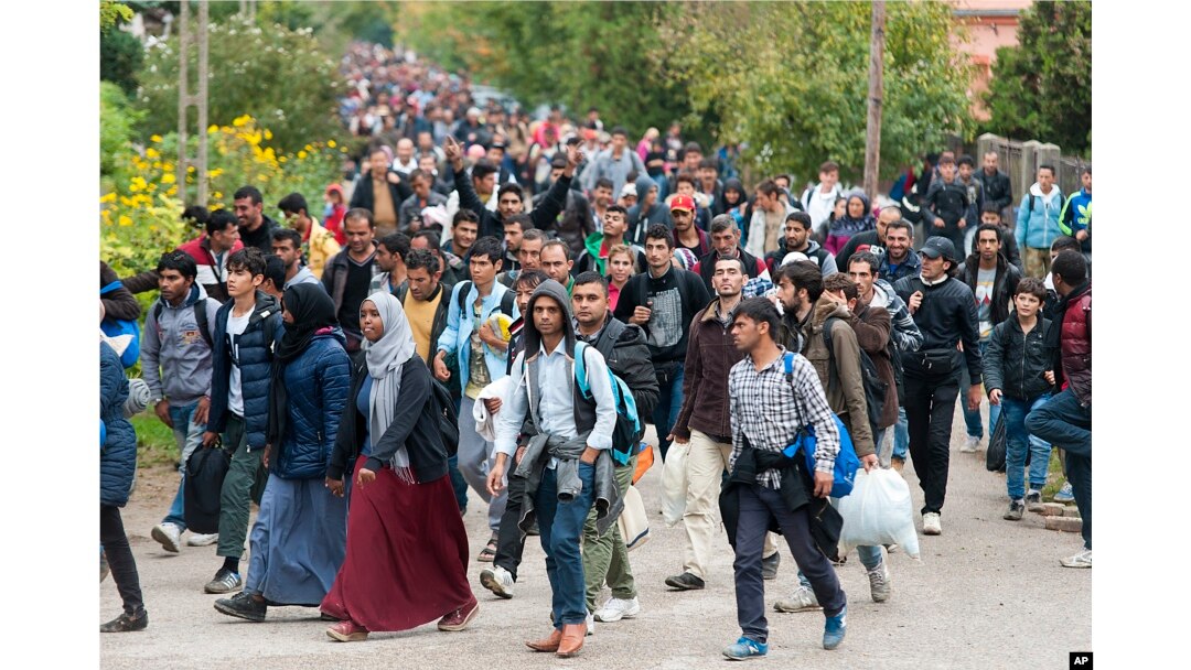 FILE - Migrants walk along a street after they arrived by train in Hegyeshalom, at the Austrian border, 169 km west of Budapest, Hungary, Oct. 7, 2015.