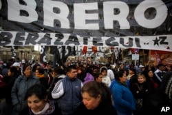 Workers march toward Plaza de Mayo with a flag that reads in Spanish "Worker" in Buenos Aires, Argentina, Aug. 22, 2017.
