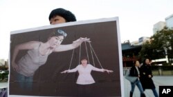 一名韩国大学生手举宣传画，展示韩国总统朴槿惠受其密友崔顺实控制