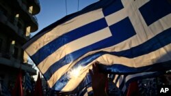 A supporter of the extreme far-right Golden Dawn political party waves a Greek flag during a pre-election rally, in Athens, Sept. 16, 2015.
