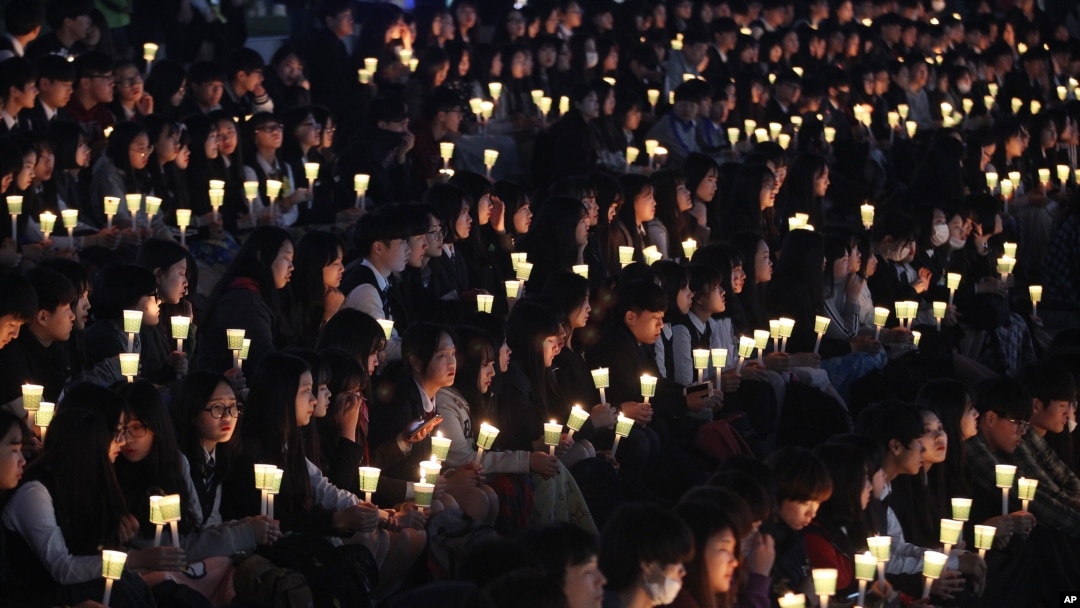 FILE – High school students in Ansan, South Korea, hold candles at a ceremony honoring victims of the Sewol ferry disaster two years earlier off the country’s southern coast.