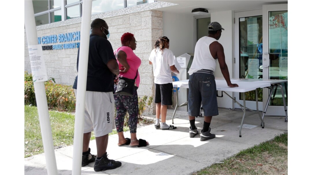 Restaurant worker Glen Pile, left, waits in line to get an unemployment form at a Miami-Dade County library during the coronavirus pandemic in Miami, April 8, 2020.