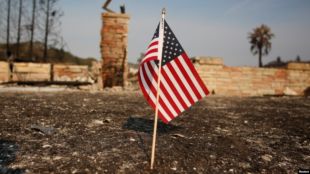 FILE - An American flag stands in front of a home destroyed after a wildfire tore through Santa Rosa, Calif., Oct. 15, 2017.