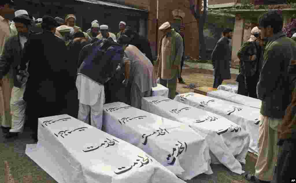 People stand near coffins of people killed in a bomb blast in the Pakistani tribal area of Khyber, December 17, 2012.