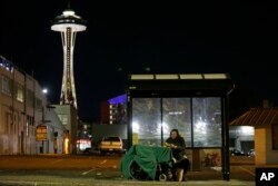Dave Chung, who says he has been homeless for five years on the streets of California and Washington state, eats a meal before bedding down in a bus shelter in view of the Space Needle in Seattle, Oct. 30, 2017.