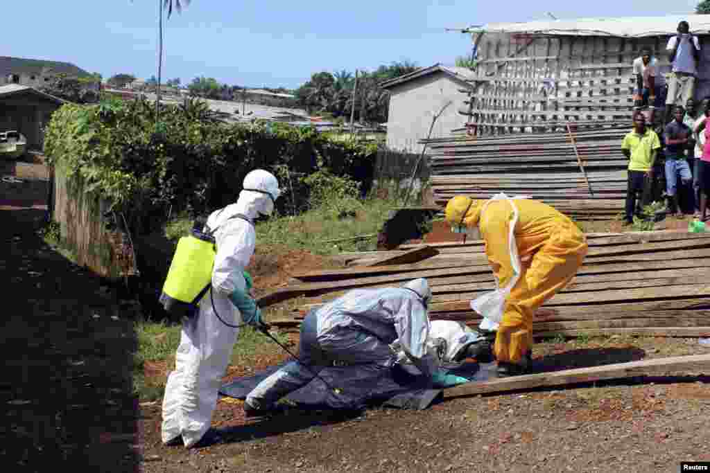 Sog'liqni saqlash xodimlari Liberiyada Eboladan o'lgan ayolning jasadini olib ketmoqda, 14-oktabr, 2014-yil.