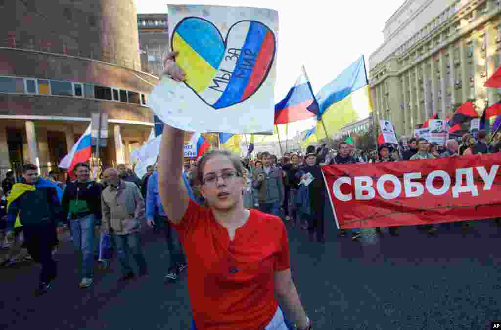 A girl carries a banner reading "we're for peace" during an anti-war rally in downtown Moscow, Russia, Sept. 21, 2014.