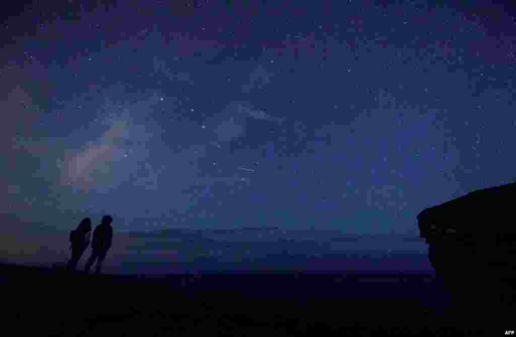 A couple enjoy Perseid meteor along the Milky Way illuminating the dark sky near Comillas, Cantabria community, northern Spain, during the "Perseids" meteor shower, Aug. 12, 2017.