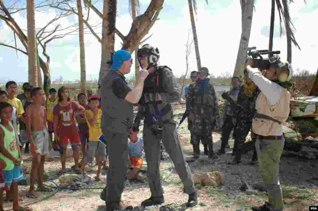 An American NGO worker pleads with a U.S. Navy helicopter crewman to bring more aid as VOA videographer Zinlat Aung videotapes the encounter in Hernani, Philippines, Nov. 19, 2013. (Steve Herman/VOA)