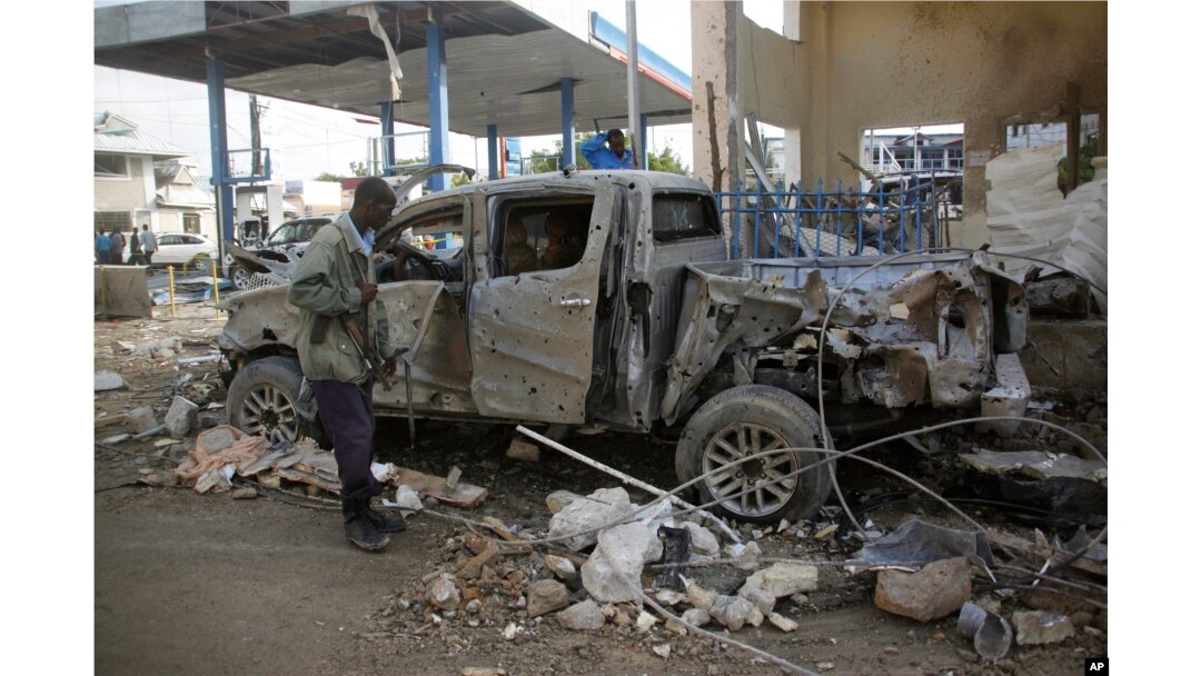 FILE - A Somali security man stands looks at the wreckage of a pickup truck near Nasa-Hablod hotel in Mogadishu, Somalia, June 26, 2016.
