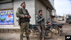 Syrian rebels sit outside Idlib, Syria, Feb. 15, 2020. Syrian troops are waging an offensive in the last rebel stronghold. 