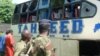 A Kenyan police officer with civilians views a Taheed Bus at the Lamu Police Station in Lamu County, July 19, 2014. 