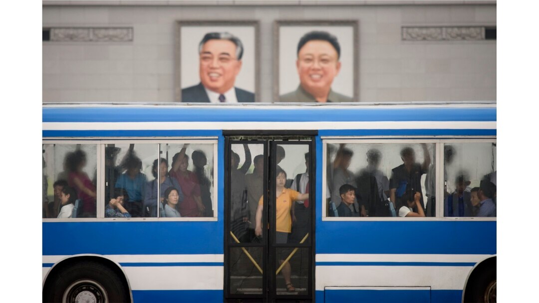 Commuters ride a bus past the portraits of late North Korean leaders Kim Il Sung and Kim Jong Il, on Kim Il Sung square in Pyongyang on June 18, 2019. (Photo by Ed JONES / AFP)