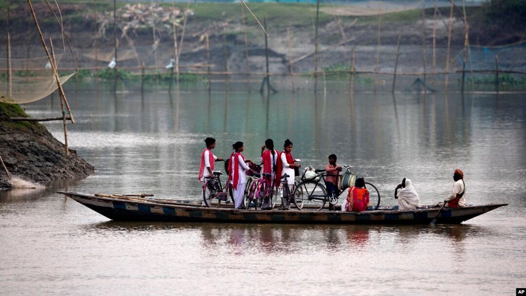 School children ride on a boat with their bicycles to cross the river Brahmaputra in Kasoshila village on the outskirts of Gauhati, India, Monday, Oct. 21, 2019. 