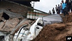 Rescuers inspect the damage in a neighborhood hit by a landslide in the village of Banaran, Ponorogo, East Java, Indonesia, April 1, 2017. More than two dozen people were reported missing Saturday after the rain-triggered landslide struck a village on Indonesia's main island of Java.