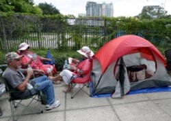 Supporters of President Donald Trump, from left, James DeWilde, Laureen Vartanian and Maureen Bailey wait in line with others on Monday, June 17, 2019, in Orlando, Fla.