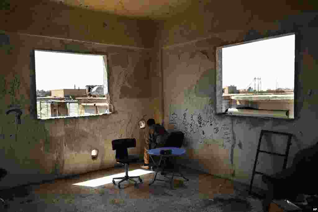 A U.S.-backed Syrian Democratic Forces fighter looks through a hole at Islamic State militant positions on the front line of the industrial district on the eastern side of Raqqa, Syria, July 26, 2017.
