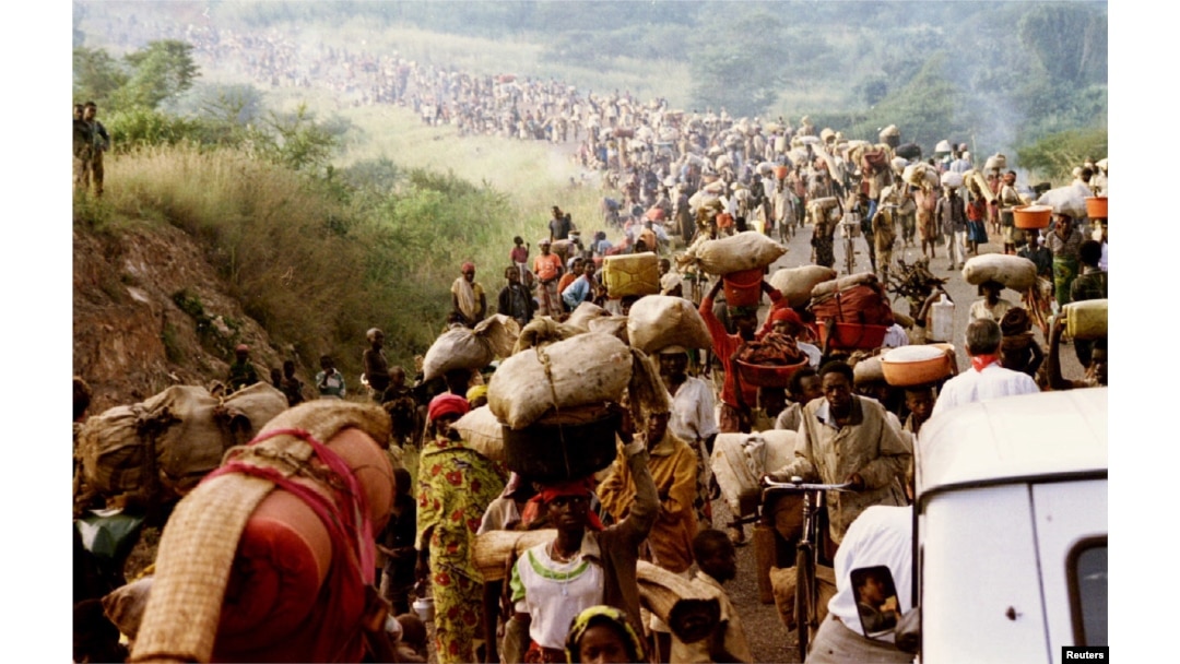 FILE - Rwandese refugees cross Rusumo border to Tanzania from Rwanda carrying their belongings even goats, mattresses and cows, May 30, 1994.
