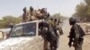 In this photo taken on Thursday, Feb. 19, 2015, Chadian soldiers on top of a truck, left, speak to Cameroon soldiers, right, standing next to the truck, on the border between Cameroon and Nigeria as they form part of the force to combat regional Islamic extremists force's including Boko Haram, near the town of Fotokol, Cameroon. 