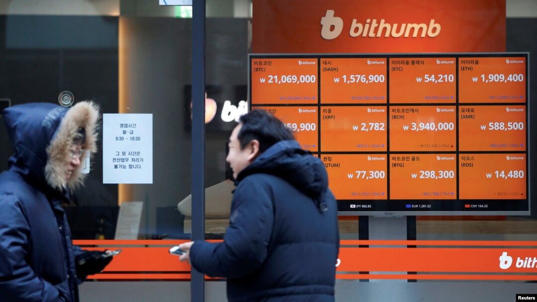 Men talk in front of an electric board showing exchange rates of various cryptocurrencies at Bithumb cryptocurrencies exchange in Seoul, South Korea, Jan. 11, 2018.