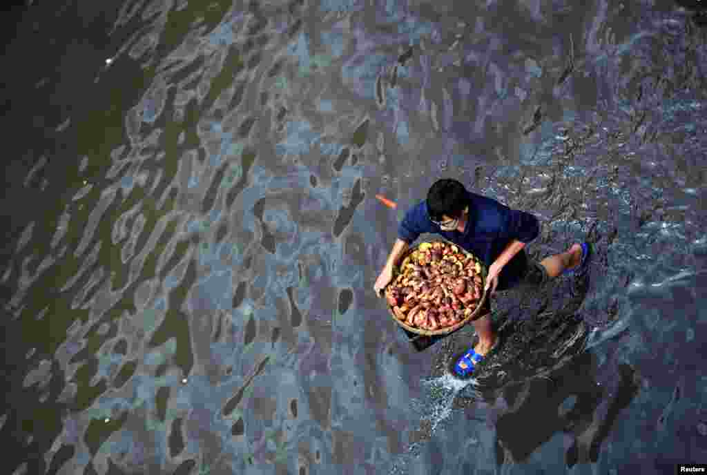 A man carries a basket with wild mushrooms on a flooded street after a rainstorm in Kunming, China July 15, 2017.