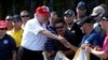 FILE - U.S. President Donald Trump gives out a commemorative "challenge coin" as he plays host to members of the U.S. Coast Guard he invited to play golf at his Trump International Golf Club in West Palm Beach, Fla., Dec. 29, 2017. Administration officials are downplaying any significance of a U.S.-North Korea coin, 250 of which were recently minted.