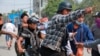 FILE - A man with a head injury is carried by fellow demonstrators during an anti-coup protest in Mandalay, Myanmar, March 22, 2021.