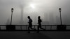 People jog past the Pudong Financial District shrouded with fog and pollution at the Shanghai Bund in Shanghai, China, April 14, 2016. 