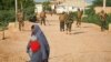 FILE - A Somali woman crosses a street while soldiers with the African Union Mission in Somalia (AMISOM) stand guard 300 kilometers west of the capital Mogadishu, on a street in Belet Weyne, Somalia. (AP)