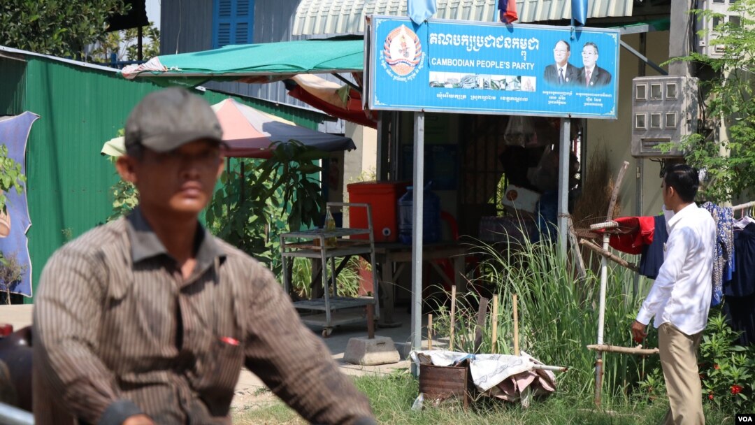 A man driving a motor passing Yim Sokhoeun’s house where a Cambodian People’s Party’s sign bearing the party logo stands in front. “It’s not good unless there is an opposition party,” said Sokhoeun, Jan. 10, 2018. (Sun Narin/VOA Khmer)
