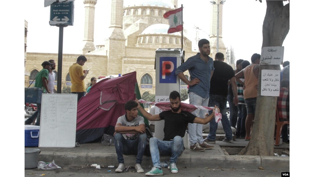 Demonstrators rest near the Ministry of Environment, where protestors have gathered to call for the resignation of Environment minister Mohammad Machnouk, Sept. 16, 2015. (J. Owens/VOA)