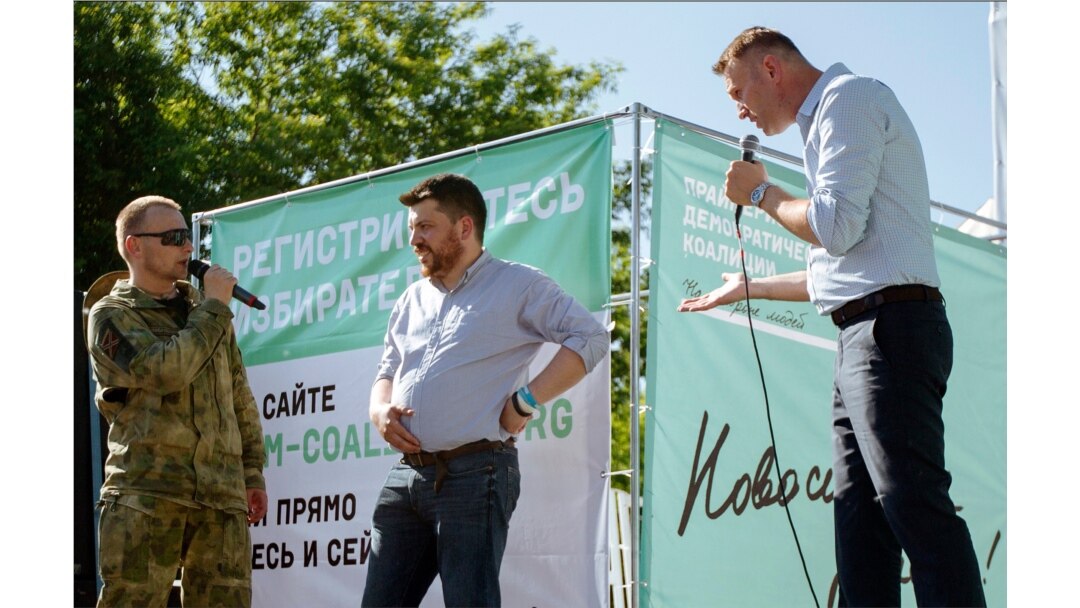 FILE - Russian opposition activist Alexei Navalny, right, argues with a man in a military uniform, left, as opposition activist Leonid Volkov, center, listens during a rally in Novosibirsk, Siberia's biggest city, Russia, June 7, 2015.