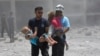 FILE - This photo provided by the Syrian civil defense group known as the White Helmets shows civil defense workers carrying children after airstrikes hit a school housing a number of displaced people, in the western part of Daraa province, Syria, June 14, 2017.